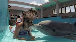 Seorang anak menerima ciuman dari lumba-lumba bernama Xinana selama sesi terapi di National Aquarium, Kuba, Senin (26/5/14). (AFP PHOTO/Adalberto ROQUE)