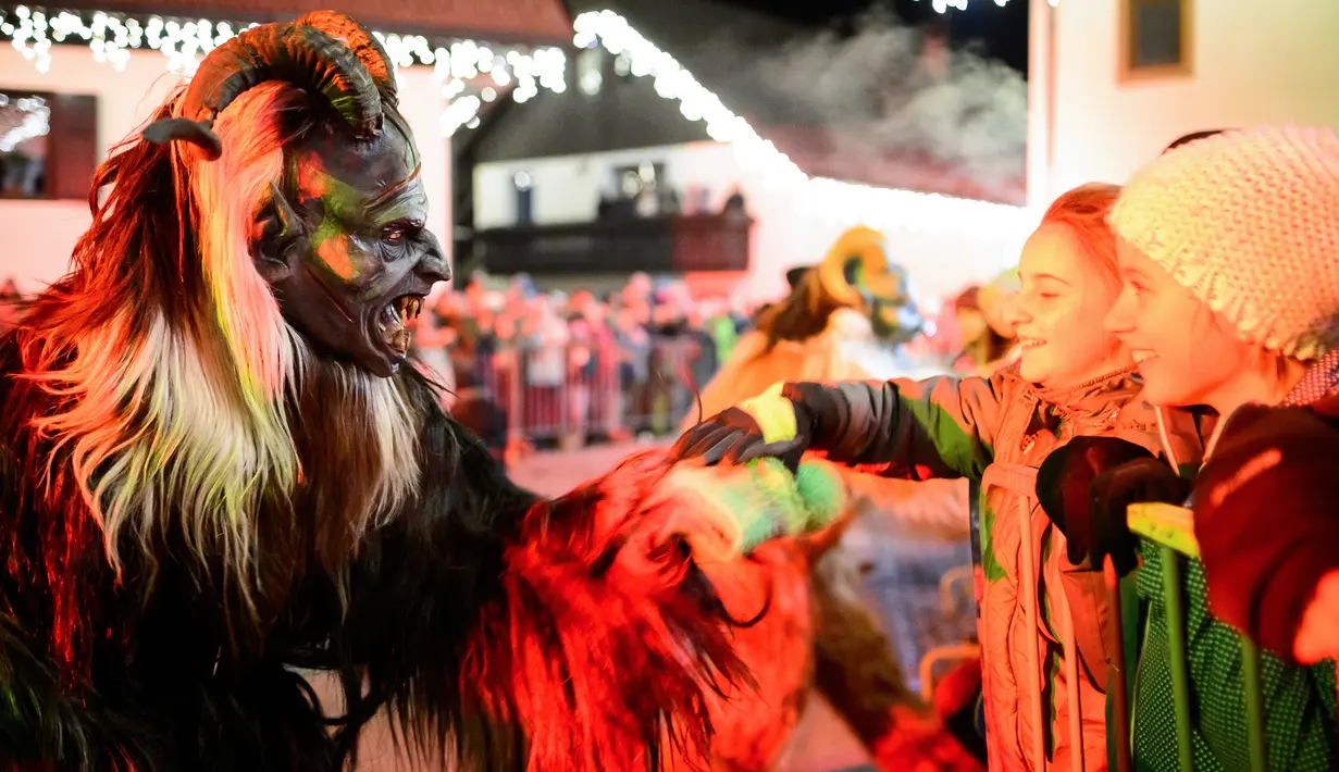 Anak-anak berbincang dengan partisipan berpakaian seperti Krampus, makhluk setengah iblis, dalam parade di Podkoren, Slovenia, Jumat (30/11). Tradisi natal ini juga dilakukan di beberapa negara seperti Austria, Jerman, Hungaria dan Ceko (Jure Makovec/AFP)
