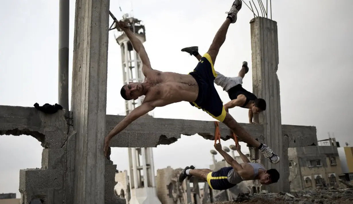 Anggota Bar Palestine, berlatih Street workout di bekas reruntuhan bangunan di kota Gaza, Palestina. Street workout adalah latihan yang dilakukan di luar ruang dengan memanfaatkan fasilitas yg ada. (AFP Photo/Mohammed Abed)