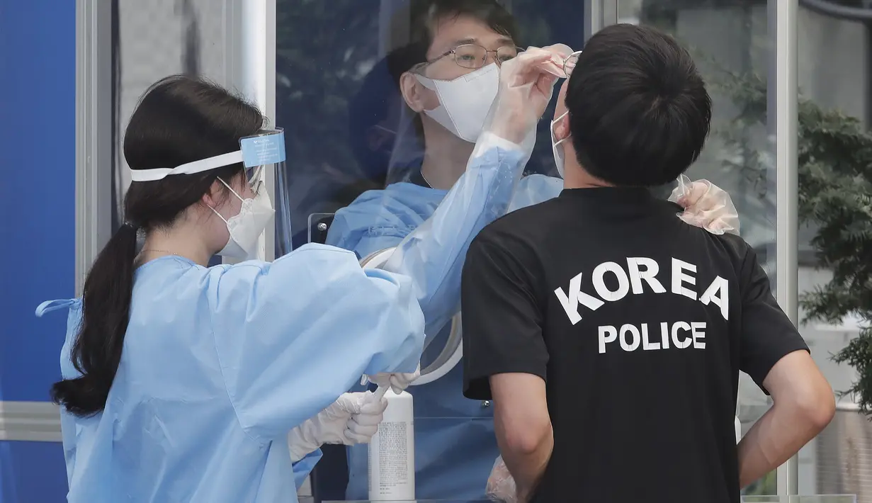 Seorang petugas medis mengambil sampel dari petugas polisi selama pengujian COVID-19 di Badan Kepolisian Metropolitan Seoul di Seoul, Korea Selatan, Rabu, (19/8/2020). (AP Photo / Ahn Young-joon)