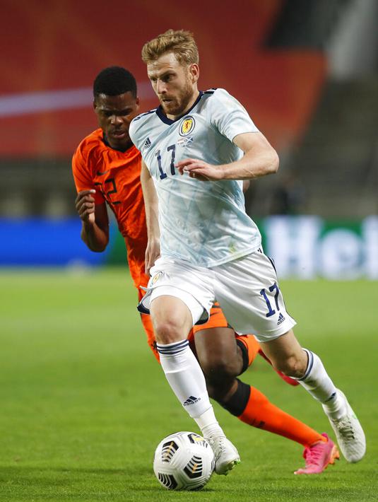 Pemain Skotlandia Stuart Armstrong (kanan) menjauhkan bola dari pemain Belanda Denzel Dumfries pada pertandingan persahabatan di Stadion Algarve, luar Faro, Portugal, Rabu (2/6/2021). Pertandingan berakhir imbang 2-2. (AP Photo/Miguel Morenatti)