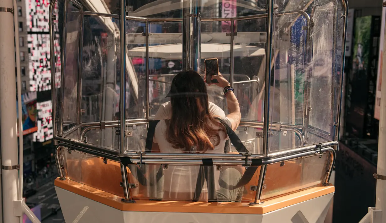 Pengunjung menikmati biangalala setinggi 110 kaki di Times Square, Manhattan, New York City, Rabu (25/8/2021). Tiket masuk umum tersedia seharga US$ 20 (Rp 287 ribu) per orang tapi dngan membayar US$ 35 (Rp 503 ribu), pengunjung dapat menghindari antrian. (Scott Heins/Getty Images/AFP)