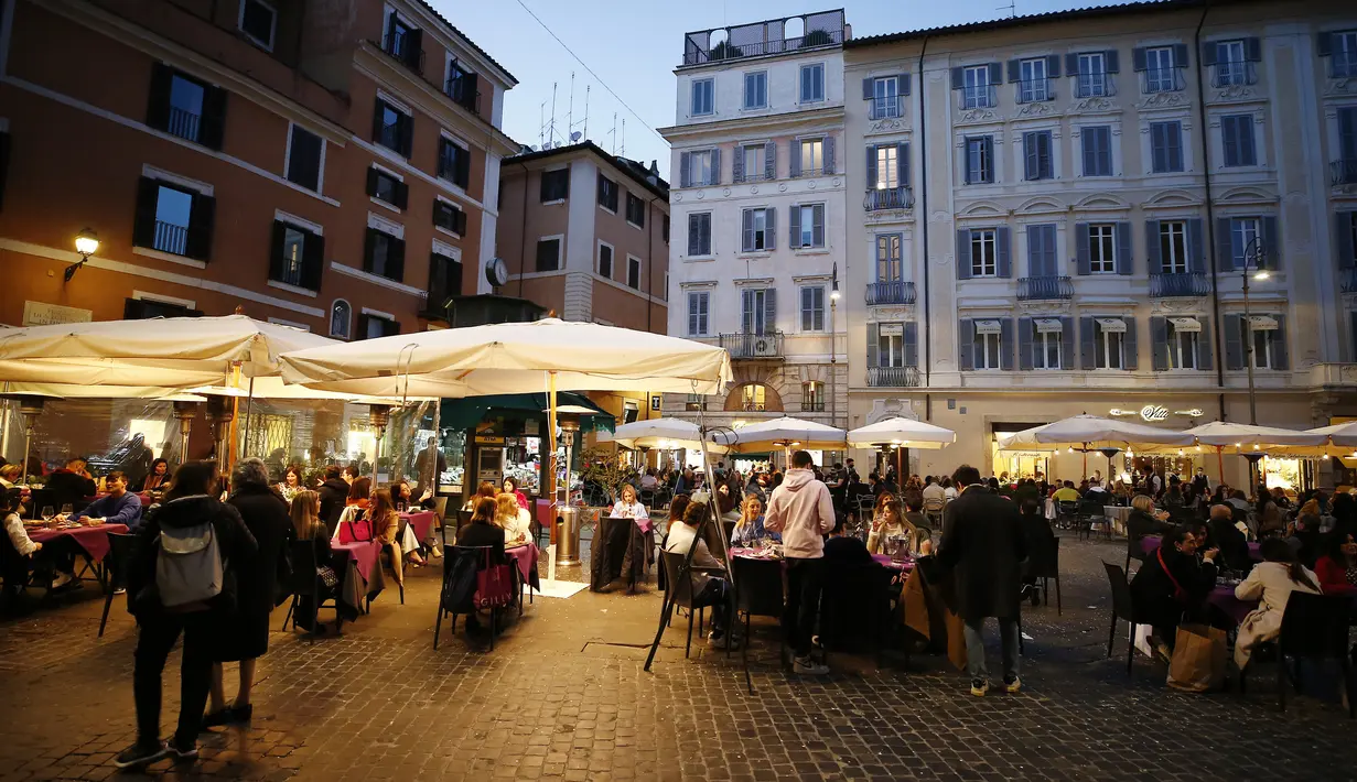 Pengunjung berbincang sambil menikmati minuman di di sebuah kafe menyusul pembatasan COVID-19 yang mulai dilonggarkan di Roma, Italia, Sabtu (6/2/2021). Pariwisata adalah sumber ekonomi Roma dan banyak orang berharap pelonggaran pembatasan jadi secercah harapan. (Cecilia Fabiano/LaPresse via AP)