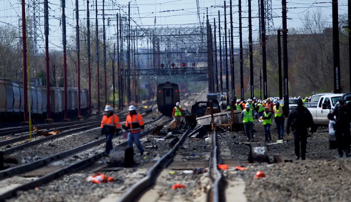 Petugas darurat dikerahkan ke lokasi kereta Amtrak yang tergelincir setelah menabrak sebuah backhoe di dekat Philadelphia, Amerika Serikat, Minggu (3/4). Dua orang tewas dan 30 lainnya mengalami luka-luka akibat kejadian ini (Mark Makela/Getty Images/AFP)