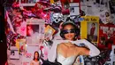 Enzy Storia tampil manis dengan mini dress putih berpotongan square neck. Penampilannya dilengkapi dengan tiara perak, kacamata hitam, dan headset hitam yang ikonik.  [@enzystoria].