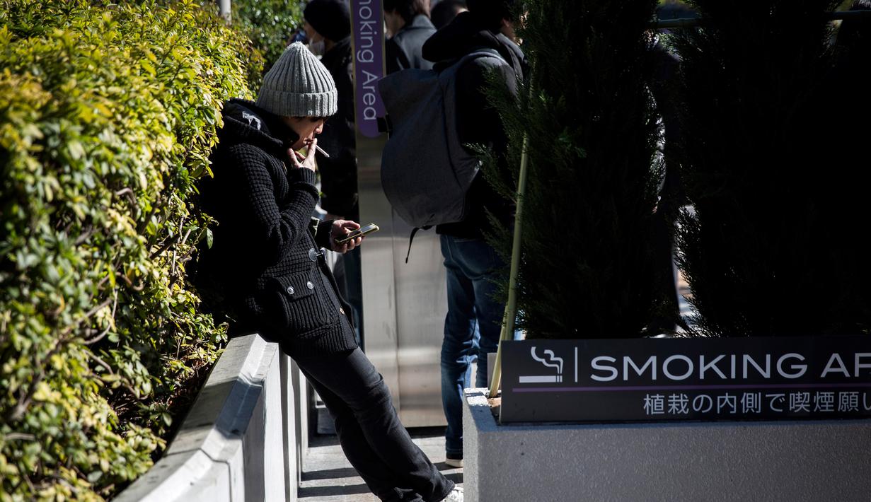Seorang pria merokok di smoking area yang disediakan di Naka-Meguro, Tokyo (10/3). Kesadaran warga Jepang termasuk tinggi dengan tertibnya para perokok yang tidak merokok di sembarang tempat. (AFP Photo/BEHROUZ MEHRI)