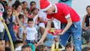 Seorang pegawai Kementerian Luar Negeri Kolombia memberikan hadiah kepada anak-anak imigran Venezuela di Cucuta, Kolombia, di perbatasan dengan Venezuela, pada Malam Natal (24/12). (AFP Photo/Schneyder Mendoza)