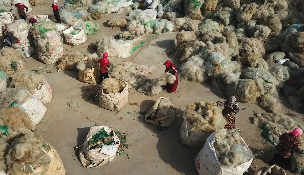 Para nelayan membersihkan jaring ikan yang dibuang untuk didaur ulang di sebuah desa di Lianyungang, di provinsi Jiangsu timur China (17/3/2021). Daur ulang jaring ikan tersebut akan dibuat palet nilon. (STR/AFP/China Out)