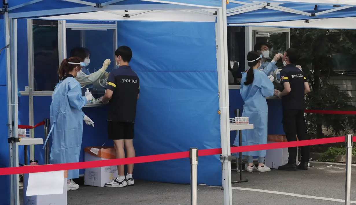 Petugas medis mengambil sampel dari petugas polisi selama pengujian COVID-19 di Badan Kepolisian Metropolitan Seoul di Seoul, Korea Selatan, Rabu, (19/8/2020). (AP Photo / Ahn Young-joon)