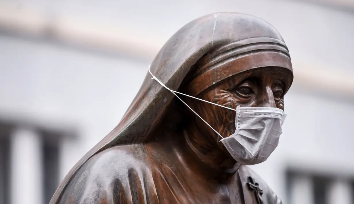 Masker terpasang pada wajah patung Bunda Teresa di Pristina, Kosovo, Kamis (19/12/2019). Selama beberapa bulan terakhir, Pristina terdaftar sebagai salah satu kota dengan kualitas udara terburuk di dunia. (Armend NIMANI/AFP)