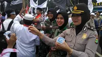 Polwan membagikan minuman kepada para pendemo saat Aksi Damai 4 November, Jakarta, Jumat (4/11). (Liputan6.com/ Richo Pramono)