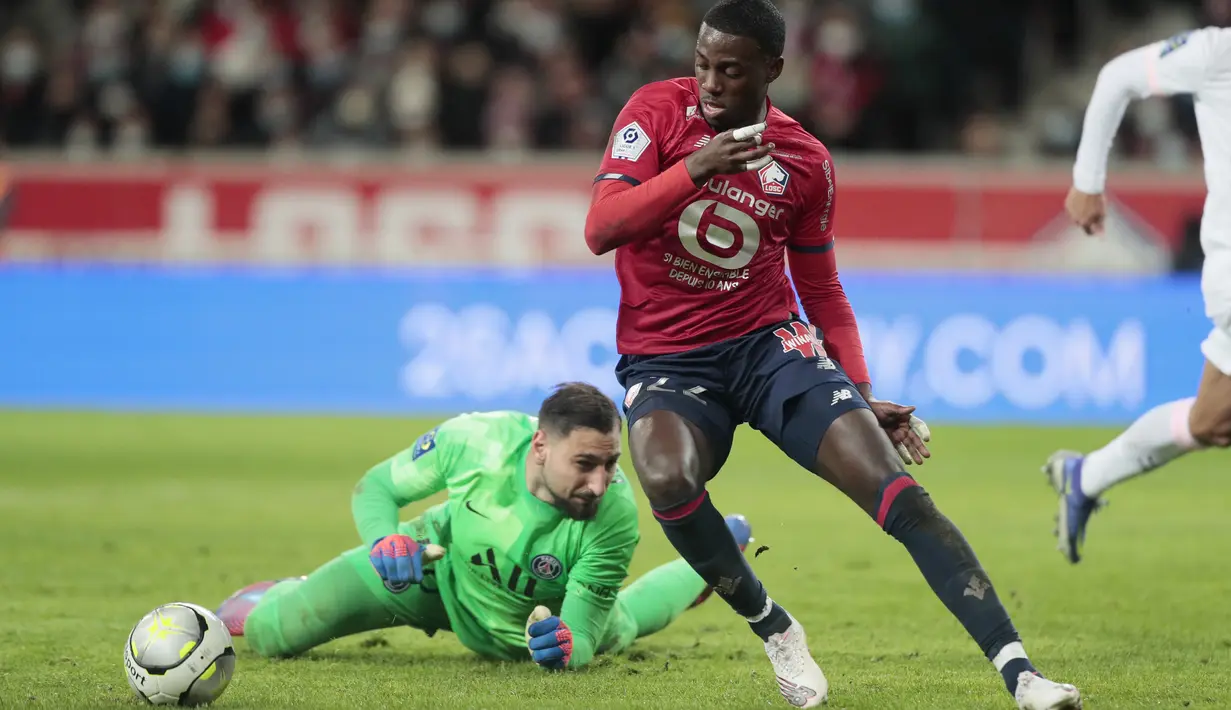 Penyerang Lille Timothy Weah menggiring bola melewati kiper Paris Saint-Germain (PSG) Gianluigi Donnarumma dalam lanjutan Liga Prancis di Stadion Pierre-Mauroy, Senin (7/2/2022) dinihari WIB. PSG mengalahkan juara bertahan Lille dengan skor 5-1. (AP Photo/Michel Spingler)
