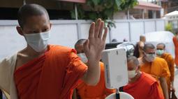 Seorang biksu memeriksa suhu tubuhnya sebelum menerima vaksin AstraZeneca COVID-19 di Wat Srisudaram di Bangkok, Thailand (30/7/2021). Thailand sedang berjuang untuk menahan wabah terbarunya yang dipicu oleh varian Delta yang sangat menular, dengan infeksi dan kematian yang meroket. (AP Photo/Sakcha