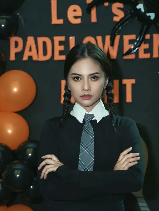 Tiwi mengenakan kostum Wednesday, dengan dress hitam kerah putih dipadukan dasi abu-abu. Rambutnya dikepang dua sesuai ciri khas karakter tersebut. [@tentangtiwi]