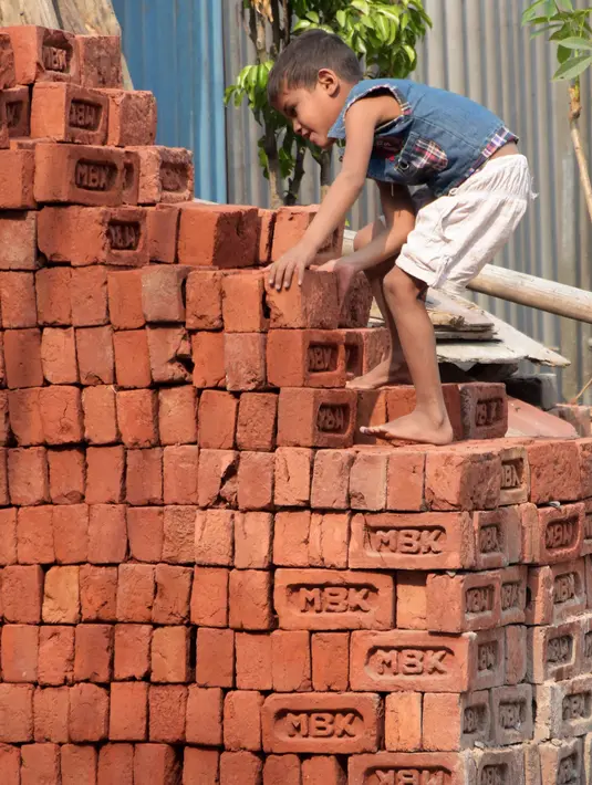 Seorang anak laki-laki bekerja di sebuah bangunan New Delhi, India, Minggu (19/11). Anak-anak bekerja sepuluh jam per hari, dan upah harian hanya sekitar 10.000 Rupiah, sepertiga dari yang diperoleh pekerja dewasa untuk pekerjaan sama. (DOMINIQUE FAGET)