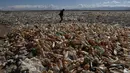Seseorang berjalan di tengah botol plastik dan sampah di daerah kering Sungai Tagaret, yang mengalir ke Danau Uru Uru, dekat Oruro, Bolivia, Kamis (25/3/2021). Sungai ini mengalir ke Danau Uru Uru dengan membawa sampah-sampah yang mencemari danau. (AP Photo / Juan Karita)