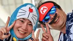 Dua suporter Jepang mengenakan kostum Doraemon  dan Mario Bros saat mendukung negaranya sebelum berlaga melawan Kolombia pada grup H Piala Dunia 2018 di Mordovia Arena di Saransk, Rusia (19/6). (AFP Photo/Mladen Antonov)