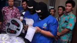 Para tersangka memegang barang bukti narkoba jenis sabu, di Kantor BNN, Jakarta, Jumat (11/6/2015). Petugas BNN berhasil mengungkap peredaran narkoba di Tebet, Jakarta dengan barang bukti sabu seberat 150 gram. (Liputan6.com/Helmi Afandi)