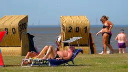 Seorang pria berjemur saat suhu mencapai 34 derajat Celcius di dekat pantai Laut Utara di Wremen, Jerman barat (24/7/2019). Peramal cuaca memprediksi suhu tertinggi di seluruh Eropa barat yang terkena gelombang panas akan mencetak rekor suhu terbaru.  (AFP Photo/Patrik Stollarz)