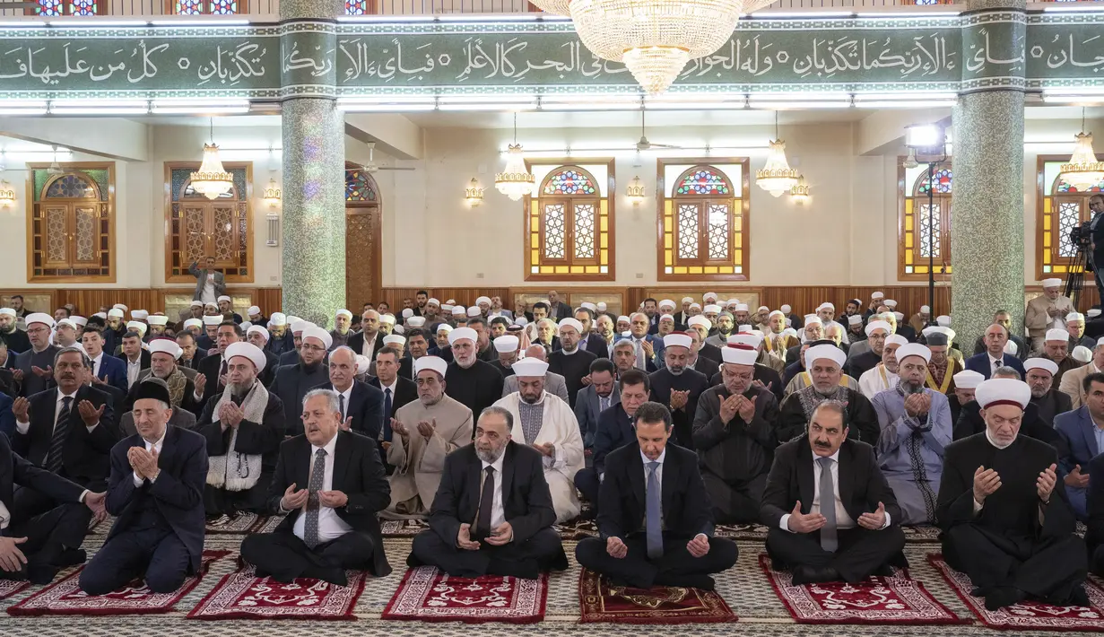 Dalam foto yang dirilis oleh kantor berita resmi Suriah SANA ini, Presiden Suriah Bashar Assad, ketiga kanan, berdoa pada hari pertama Idul Fitri, yang menandai akhir bulan suci Ramadhan di topeng Hafez Assad di Damaskus, Suriah, Jumat, 21 April 2023. (AP Photo)