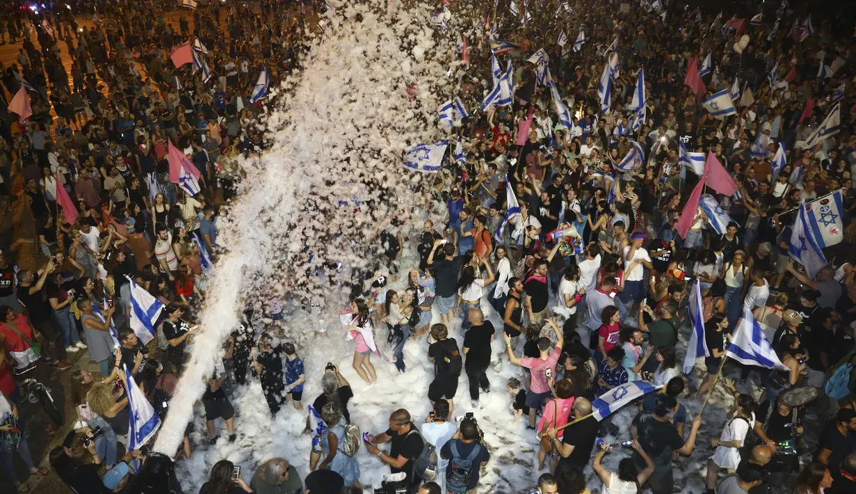 Warga Israel merayakan pelantikan pemerintahan baru di Tel Aviv, Israel, Minggu (13/6/2021). Parlemen Israel telah memberikan suara mendukung pemerintahan koalisi baru yang secara resmi mengakhiri 12 tahun pemerintahan bersejarah Perdana Menteri Benjamin Netanyahu. (AP Photo/Oded Balilty)