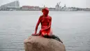 Cat merah menutupi tubuh patung putri duyung 'Little Mermaid' Mermaid' yang menjadi korban vandalisme di Kopenhagen, Denmark, Selasa (30/5). Kepolisian Denmark tengah menyelidiki kasus perusakan patung bersejarah ini. (Jens Dresling/Ritzau Foto via AP)
