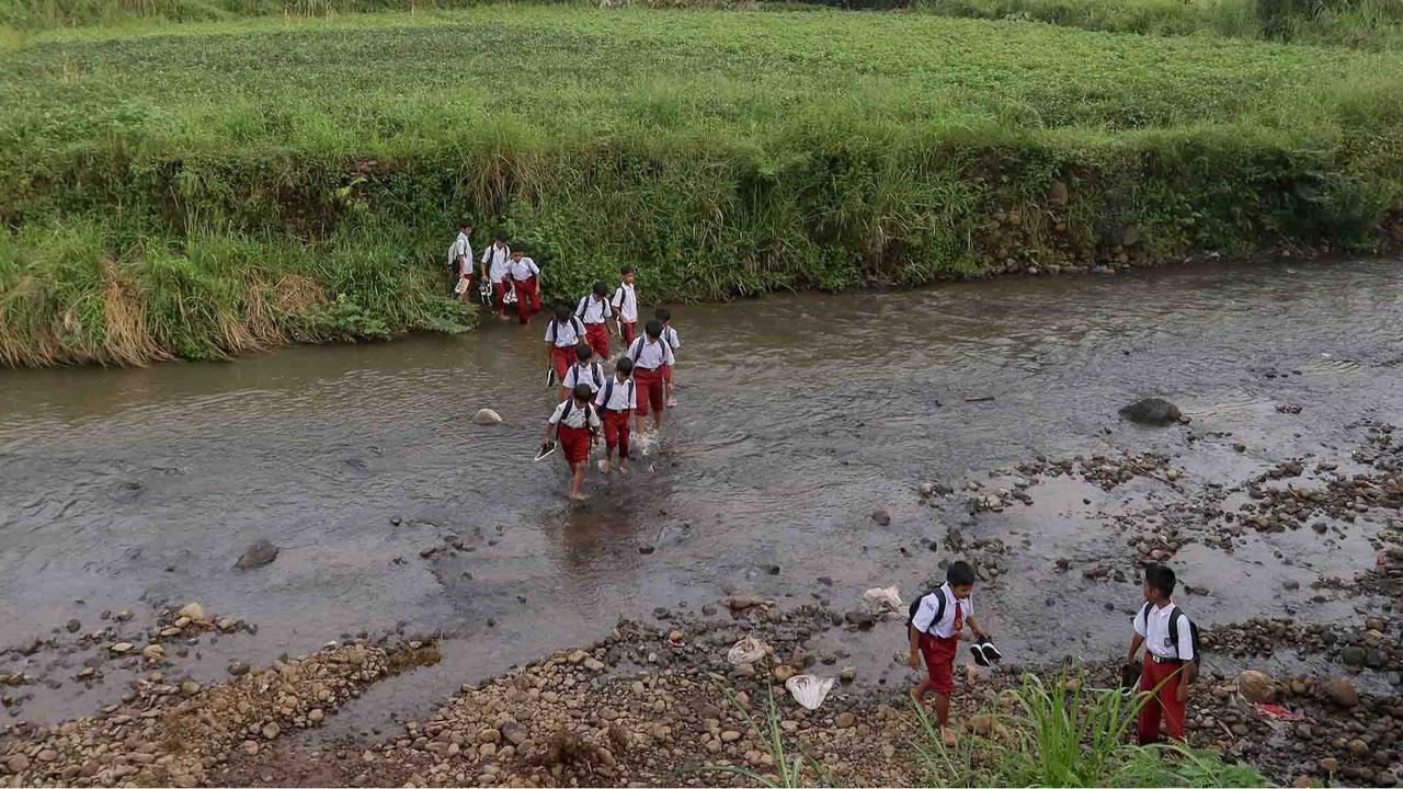 FOTO: Ketiadaan Jembatan  Penghubung Membuat Puluhan Siswa Menyeberang Sungai Menuju Sekolah di Dramaga Bogor