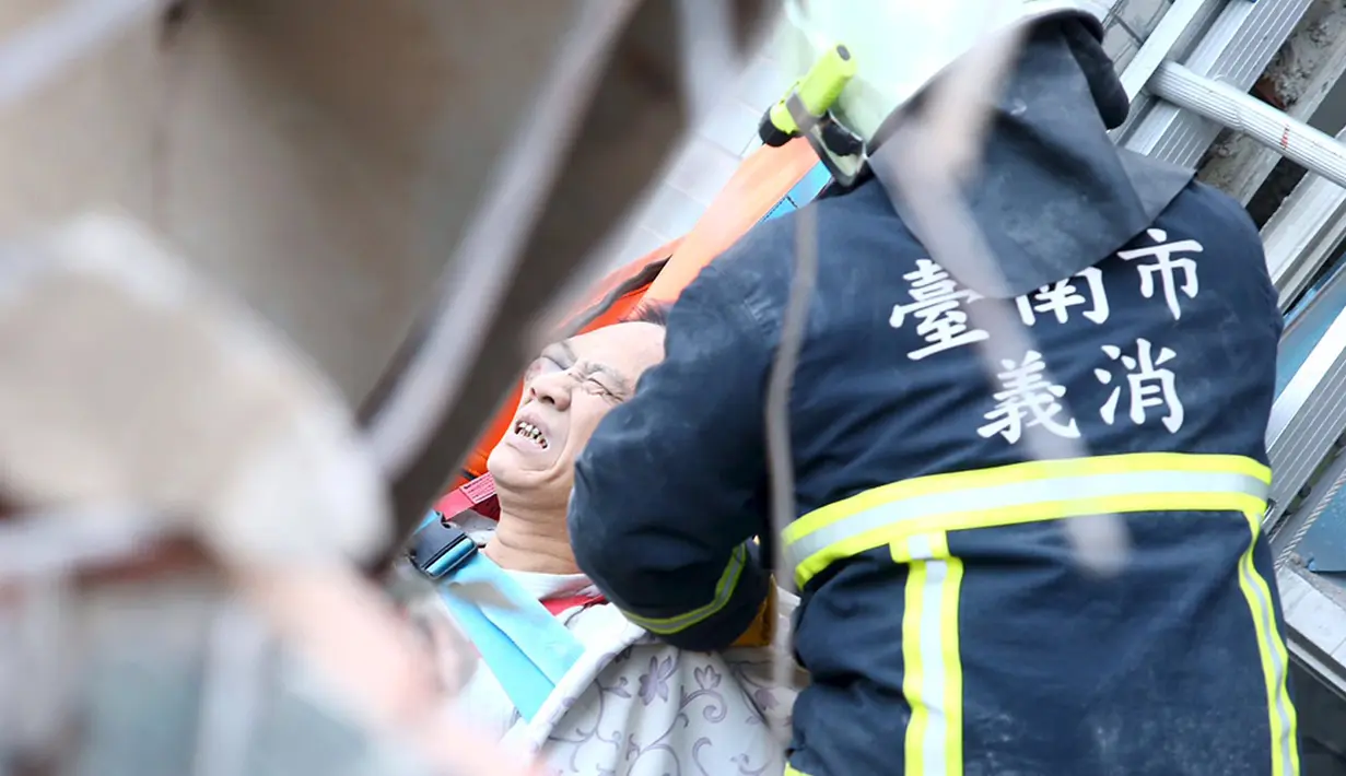 Petugas penyelamat mengevakuasi seorang korban di gedung apertemen yang runtuh akibat gempa 6,4 SR  di Tainan, (6/2). Menurut data meteorologi gempa terjadi pada kedalaman 16,7 kilometer di bawah permukaan laut. (REUTERS/Stringer)