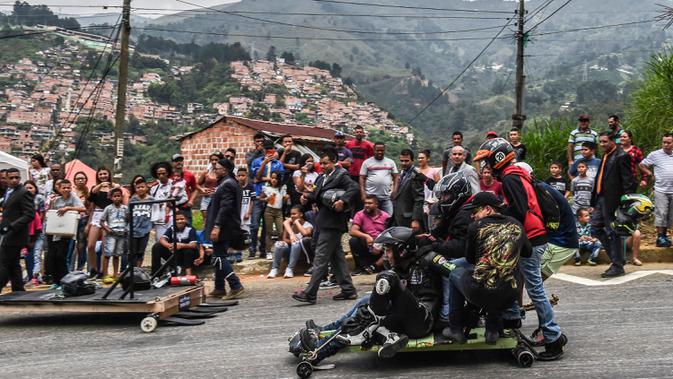 Para peserta menuruni bukit menggunakan kendaraan buatan mereka sendiri dalam festival kendaraan luncur dengan nama Car Festival di Medellin, Kolombia, 17 November 2019. Car Festival ke-30 ini menggunakan gerobak buatan yang dibuat mirip seperti mobil. (JOAQUIN SARMIENTO/AFP)