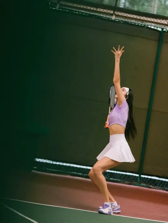 Anya Geraldine mengenakan pakaian crop top ungu yang dipadukan mini skirt putih