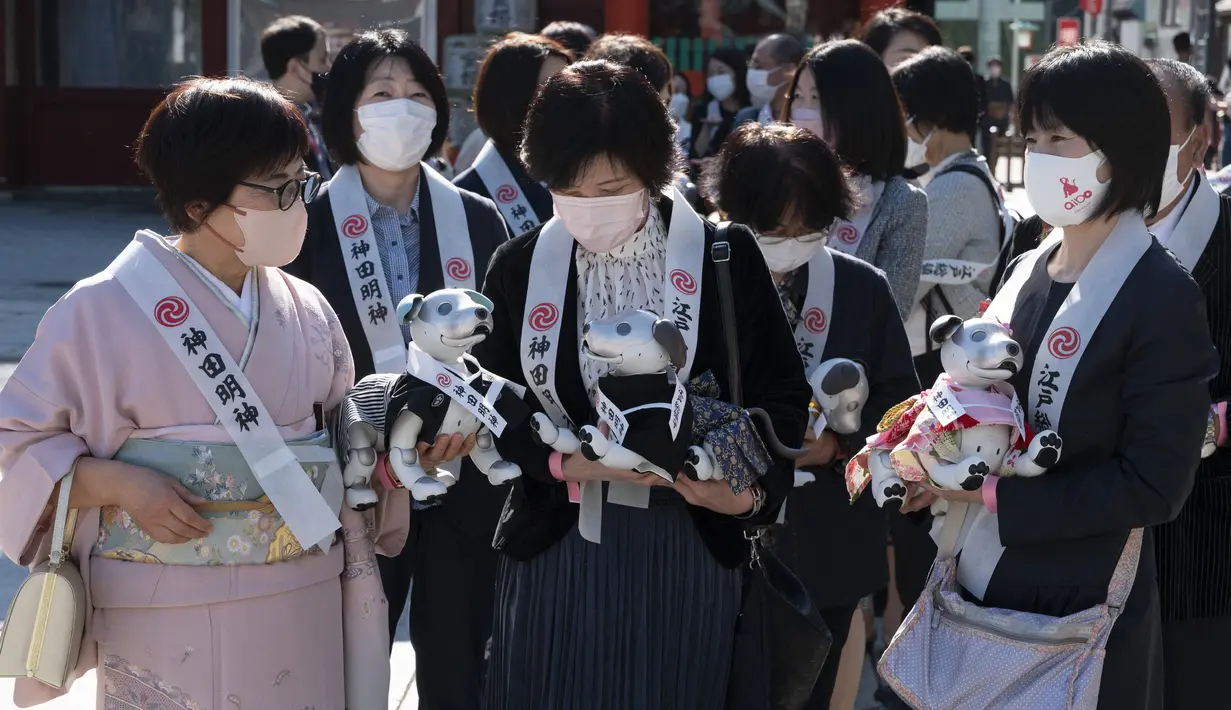 Pemilik robot anjing "aibo" menunggu untuk melanjutkan ke aula kuil untuk menandai Festival Shichi-Go-San di Kuil Kanda Myojin, Tokyo, Jepang, Jumat (11/11/2022). Lebih dari 60 pemilik "aibo" menghadiri acara tradisional yang diadakan setiap tahun dengan mendoakan kesehatan yang baik di masa depan untuk anak perempuan berusia tiga dan tujuh tahun dan anak laki-laki berusia lima tahun. (Richard A. Brooks / AFP)