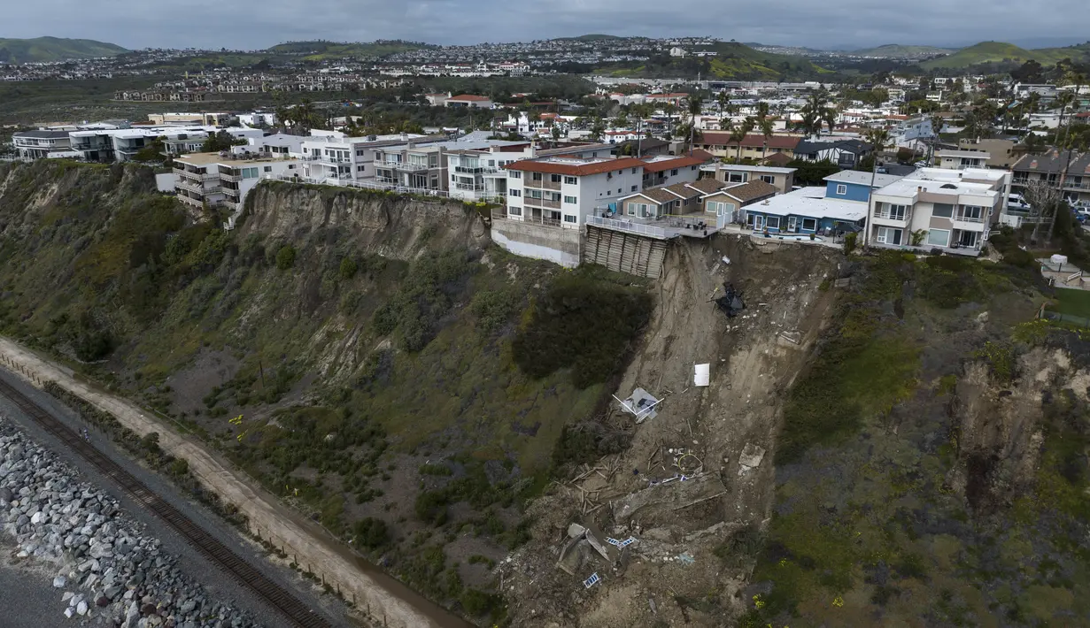 Hujan berminggu-minggu mengendurkan tanah di Orange County yang jatuh di dekat rel kereta api yang membentang di sebelah pantai di bawah. (AP Photo/Jae C. Hong)