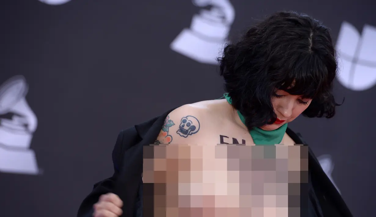 Penyanyi Chile Mon Laferte membuka bajunya saat berpose di karpet merah Latin Grammy Awards 2019, MGM Grand Garden Arena, Las Vegas, Amerika Serikat, Kamis (14/11/2019). Aksi Mon merupakan bentuk pernyataan politik atas situasi kekerasan dalam demonstrasi di negaranya. (Bridget BENNETT/AFP)