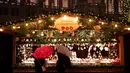 Wisawatan menggunakan payung saat mengunjungi pasar Natal di luar City Hall, Wina pada 26 November 2018. Di Pasar Natal ini, para pengunjung bisa menikmati jajanan khas hingga pernak-pernik kerajinan tangan asli Austria. (JOE KLAMAR / AFP)