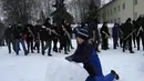 Seorang anak laki-laki membuat bola salju sementara penduduk setempat mengambil bagian dalam pelatihan pertahanan militer di Kyiv, Ukraina (30/1/2022). Menteri Luar Negeri Sergey Lavrov juga menantang klaim NATO sebagai struktur pertahanan murni. (AP Photo/Efrem Lukatsky)