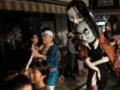 Peserta mengenakan kostum hantu saat festival Awa Odori di Kota Miyoshi, Jepang (16/8). Awa Odori yang memiliki sejarah 400 tahun ini selalu menarik ribuan pengunjung dan penari ke Tokushima pada pertengahan Agustus. (AFP Photo/Yasuyoshi Chiba)