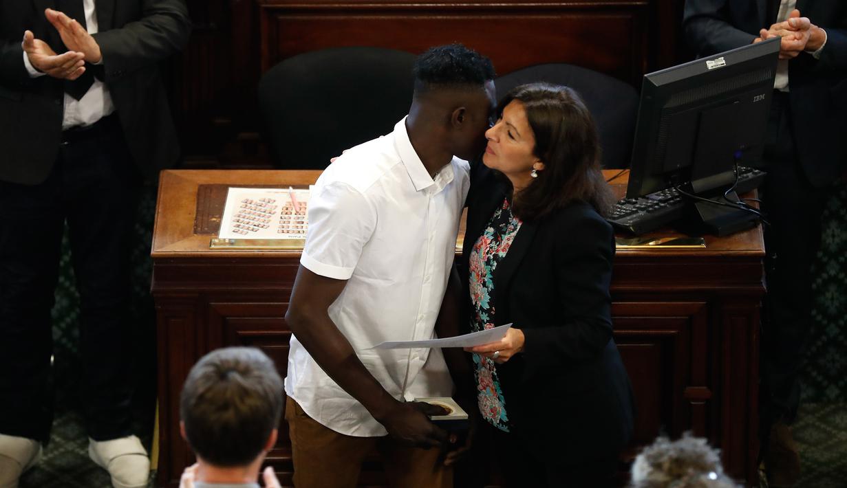 Imigran Mali Mamoudou Gassama (tengah) saat menerima medali Grand Vermeil yang diberikan walikota Paris Anne Hidalgo (kanan) di Paris, Prancis (4/6). Berkat aksi heroiknya ia menerima medali Grand Vermeil. (AFP/Francois Guillot)