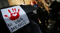 Seorang perempuan menempelkan tanda "Ni Una Menos" di payungnya dalam aksi unjuk rasa di Buenos Aires (Reuters)