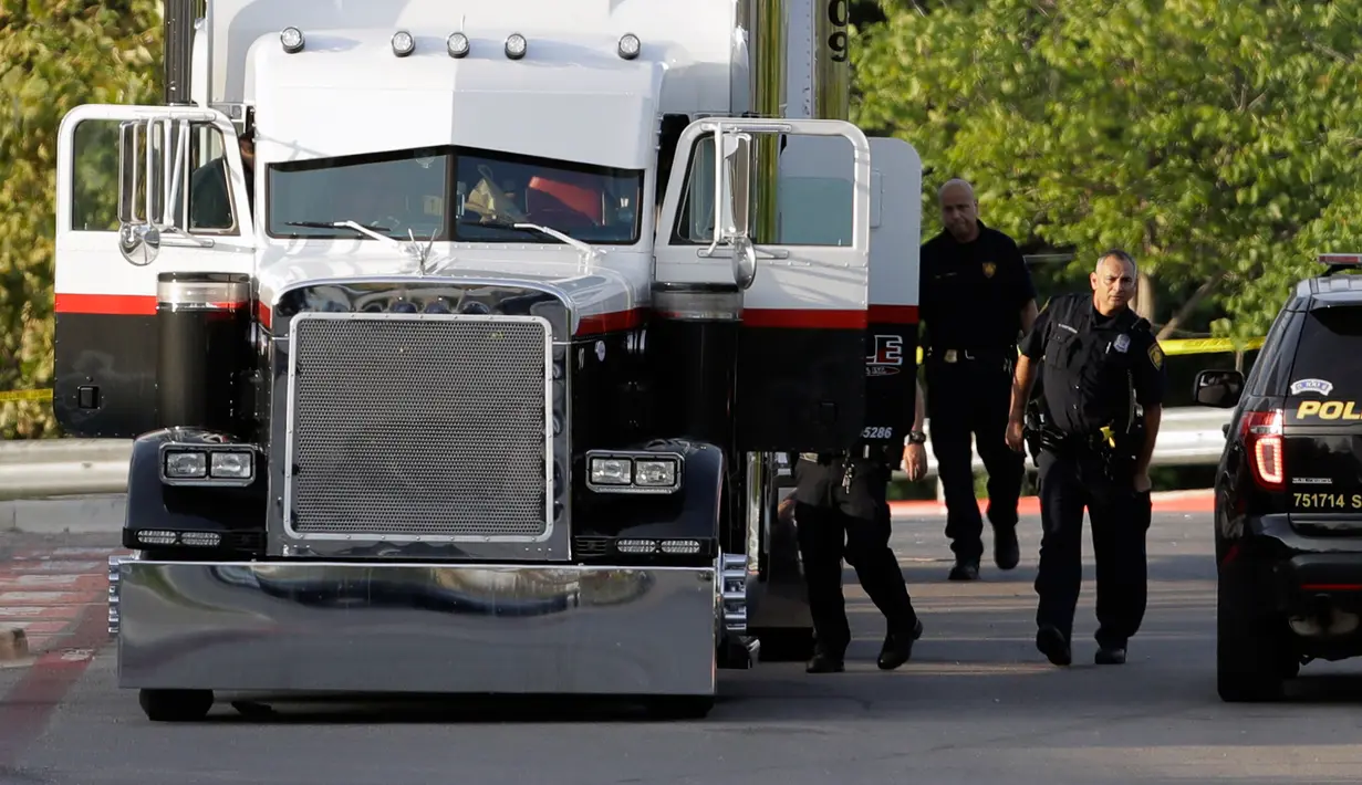 Polisi San Antonio selidiki truk yang berisi sembilan mayat di lapangan parkir sebuah supermarket, Texas, Minggu (23/7).  Selain menemukan korban tewas, 30 orang lainnya juga diselamatkan di dalam truk itu, 17 dalam kondisi kritis. (AP Photo/Eric Gay)