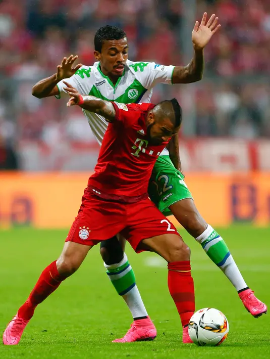 Gelandang Muenchen, Arturo Vidal (kanan) berusaha melewati gelandang Wolfsburg, Luiz Gustavo pada bundesliga di Allianz Arena, Rabu (23/9/2015). Muenchen menang telak atas Wolfsburg dengan skor 5-1. (AFP PHOTO/Michaela Rehle)