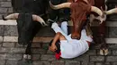 Seorang pengunjung festival terjatuh di depan banteng-banteng aduan Victoriano del Río saat acara lari banteng ketiga di festival San Fermín di Pamplona, Spanyol, Kamis, 9 Juli 2026. (AP Photo/Miguel Oses)