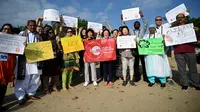 Massa mengangkat plakat saat kampanye perubahan iklim global di Pantai Sanur, Bali, Jumat (20/9/2019). Aksi ini diikuti oleh ratusan pekerja muda dari 21 negara Asia Pasifik yang tergabung dalam federasi serikat pekerja global Public Services International (PSI). (SONNY TUMBELAKA/AFP)