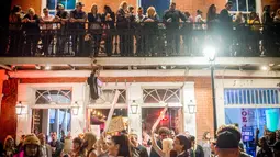Warga melihat para demonstran yang sedang melakukan aksi di Bourbon Street, New Orleans (1/2). Sebelumnya delapan klub di New Orleans telah ditutup karena pelanggaran prostitusi dan narkoba. (AFP/Emily Kask)