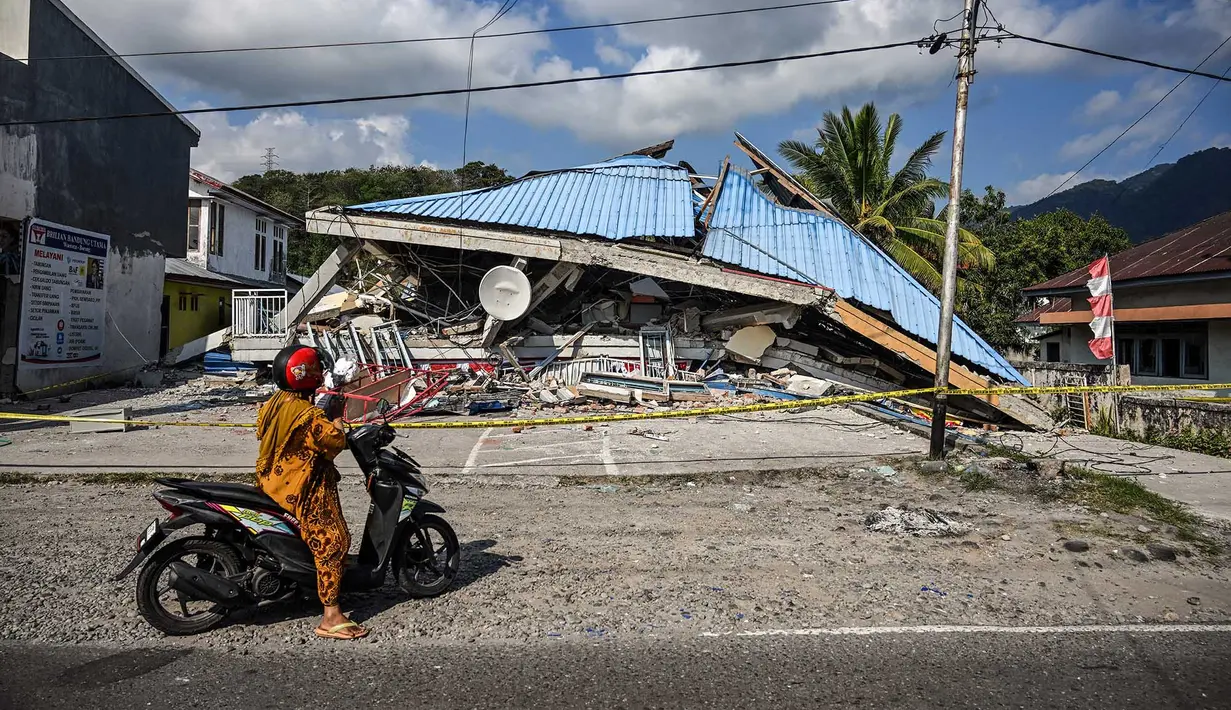 Sebuah sepeda motor berhenti di dekat bangunan yang runtuh pascagempa berkekuatan magnitudo 7,7 di Borong, Manggarai Timur, Nusa Tenggara Timur, Minggu, 16 Agustus 2026.. (AFP/ Juni Kriswanto)