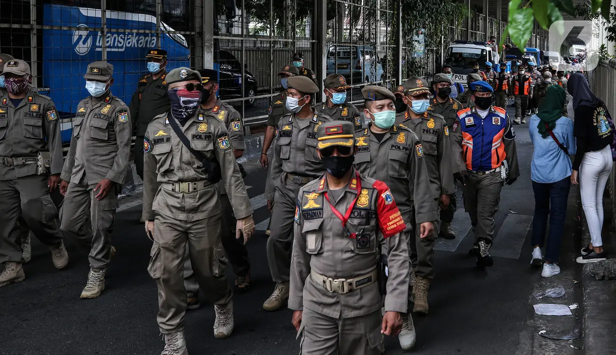 Aparat gabungan melakukan penertiban kepada pedagang yang berjualan di trotoar di kawasan Tanah Abang, Jakarta, Minggu (2/5/2021). Selain merazia barang dagangan pedagang, aparat gabungan juga menegur warga yang tidak menerapkan protokol kesehatan. (Liputan6.com/Johan Tallo)