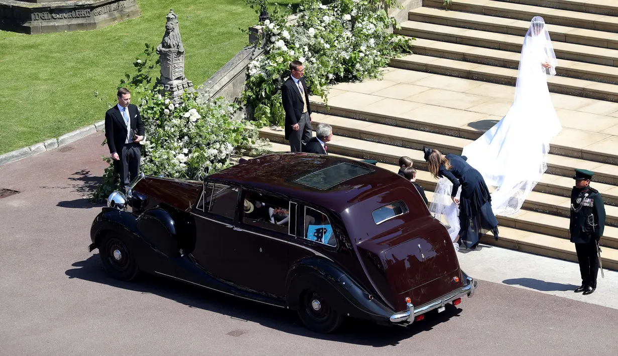 Meghan Markle turun dari mobil saat akan melangsungkan upacara pernikahan dengan Pangeran Harry di St George's Chapel, Kastil Windsor, Windsor, Inggris, Sabtu (19/5). (Andrew Matthews/POOL/AFP)
