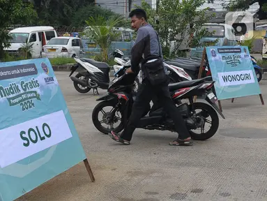 Warga calon pemudik mendorong motor yang hendak diangkut menuju kampung halaman di Terminal Pulogadung, Jakarta, Selasa (2/4/2024). (merdeka.com/Imam Buhori)