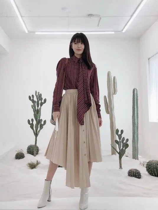 Shirt bernuansa striped dengan detail tali depan, bisa jadi statement untuk midi skirt berpotongan asimetris dan ankle boots. (Instagram/sooyoungchoi).
