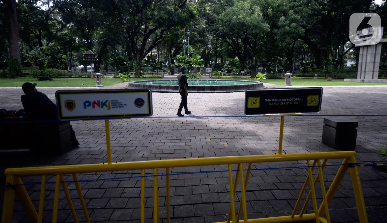 Petugas berjaga di dalam pembatas tulisan tanda ditutup sementara untuk mencegah penyebaran virus Covid-19 di Taman Suropati, Menteng, Jakarta, Senin (21/12/2020). (merdeka.com/Dwi Narwoko)