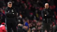 Pelatih Manchester United, Ole Gunnar Solskjaer (kiri) dan pelatih Manchester City, Pep Guardiola menyaksikan pemainnya bertanding pada leg pertama semifinal Piala Liga Inggris di Old Trafford (7/1/2020). City menang 3-1 atas MU. (AFP/Paul Ellis)